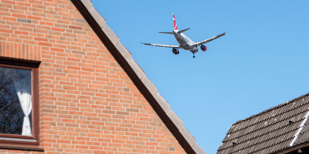 Ein Flugzeug fliegt über einem Einfamilienhaus