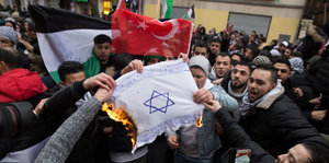 Männer verbrennen eine selbstgemalte Israelfahne