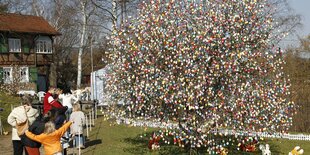 Familie und Baum mit bunten Ostereiern