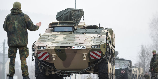 Ein Bundeswehrsoldat hält stoppend die rechte Hand vor einen Panzer