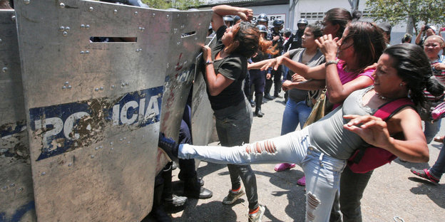Mehrere Frauen kämpfen gegen eine Polizeisperrung an