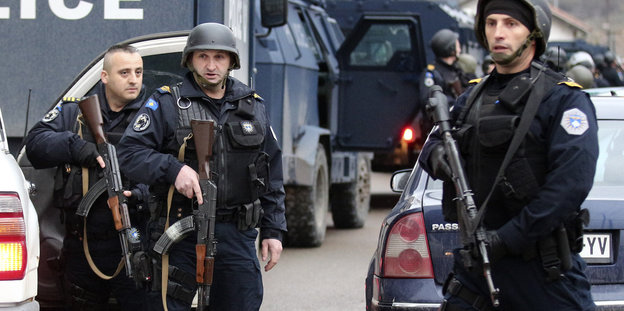 Polizisten mit Maschinengewehren blockieren eine Straße