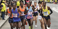 Mehrere Männer in Sportkleidung laufen einen Marathon, am Srraßenrand ist Publikum