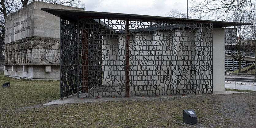 Ein Denkmal mit marschierenden Soldaten und eines mit einem Text aus gegossenen Buchstaben.