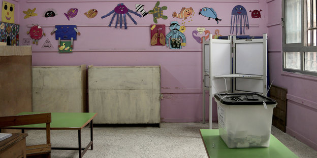 Ein Schul- oder Kindergarten-Raum, mit Wahlurne auf einem Tisch und ausgeschnittenen Tierbildern an der Wand