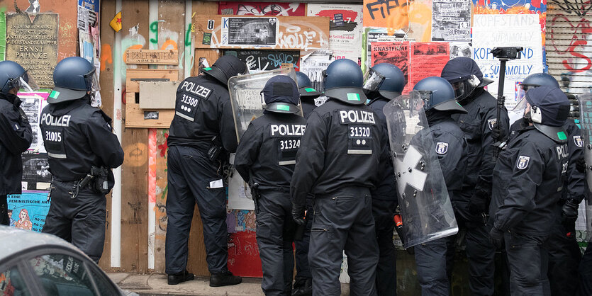 Mehrere Polizisten in Riotgear vor einem Hauseingang