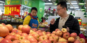 Zwei Menschen stehen in einem Supermärkt vor Äpfeln