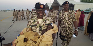 Ein General trägt ein zurückgebrachtes Mädchen, das von der Boko-Haram-Miliz entführt wurde