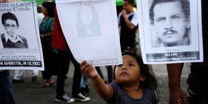 Ein Kind greift nach dem Bild einer verschwundenen Person in Gutaemala