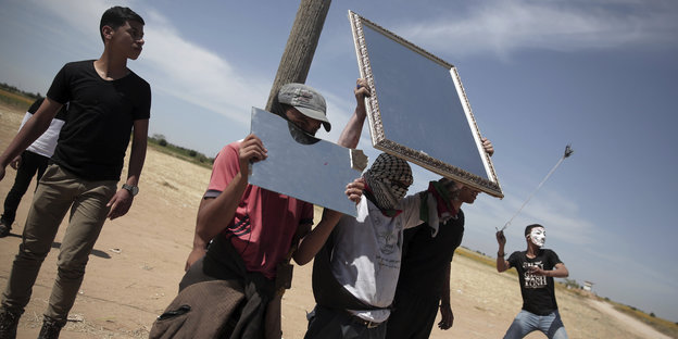 Palästinensische Demonstranten nutzen Spiegel, um Sonnenlicht auf israelische Soldaten im gazastreifen zu reflektieren