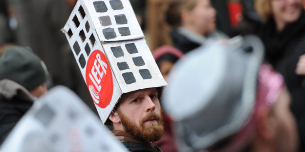 Mann protestiert mit einem Hut in Hausform
