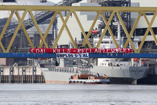 Ein Schiff, das Kohle transportiert, fährt durch einen Hafen.