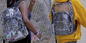 Eine Schülerin und ein Schüler tragen durchsichtige Rucksäcke