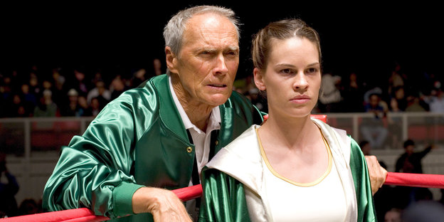 Clint Eastwood steht neben Hilary Swank, die im Boxring steht