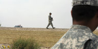 Zwei Soldaten patroullieren auf einem Feld