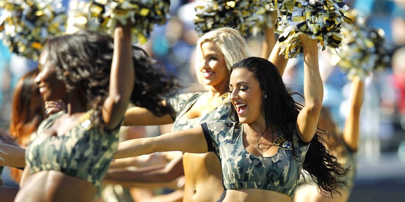 Eine Gruppe Cheerleader tanzt mit Goldenen PomPoms