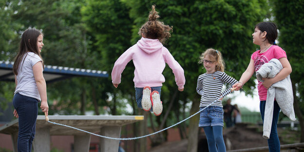 Vier Mädchen springen Seil