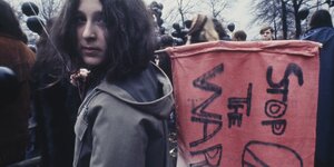 Ein junge Demonstrant hält eine rote Flagge mit der Aufschrift „Stop the War" und dem Peace-Zeichen