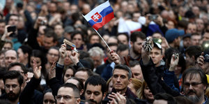 Menschen stehen dicht gedrängt, einer hält eine slowakische Flagge hoch