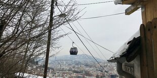 Die Gondel einer Bergstation hängt über der Stadt