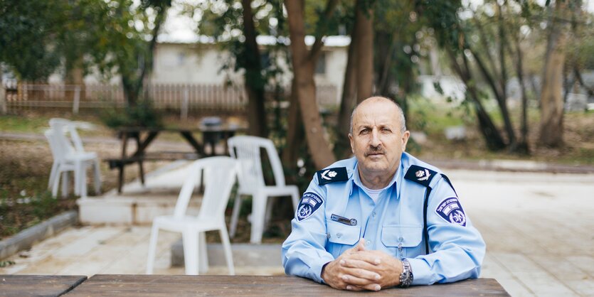 Ein Polizist sitzt unter Bäumen