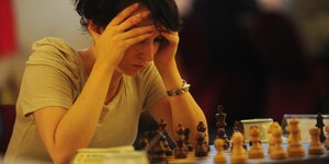 Elisabeth Pähtz sitzt vor einem Schachbrett. Sie hat den Kopf in die Hände gestützt
