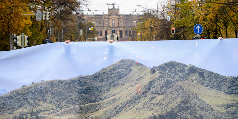 Leute halten ein Transparent hoch, auf dem Berge zu sehen sind