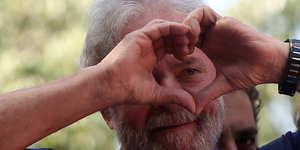 Lula mit einem zum Herzsymbol geformten Fingern