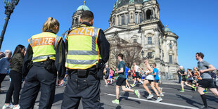 Zwei Polizisten stehen an der Halbmarathonstrecke in Berlin vor dem Dom.