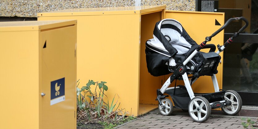 Ein Kinderwagen steht vor einem Kasten