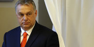 Viktor Orban kommt neben einem Vorhang hervor