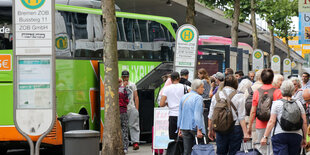 Menschen mit Koffern gehen auf wartende Busse zu.