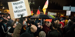 Demonstranten mit Deutschlandfahnen und "Merkel muss weg"-Schild.