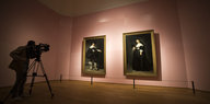 Ein Kameramann vor zwei Porträts in einem Museum