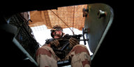 Ein Soldat sitzt auf einem Militärfahrzeug und hält ein Gewehr in der Hand