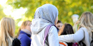 Ein Mädchen mit Kopftuch vor einer Gruppe von Mädchen ohne Kopftuch