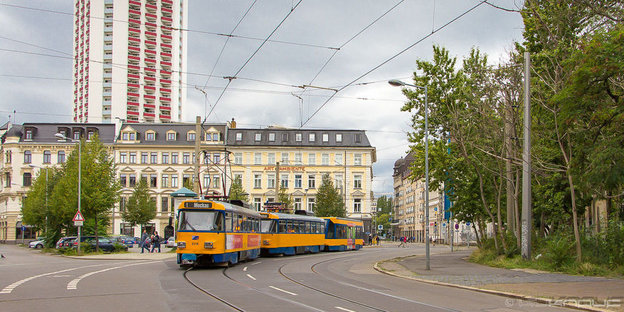 Eine Straßenbahn fährt vor einer Häuserzeile um die Kurve.