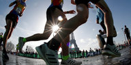 Beine von Marathonläufern vor dem Eifelturm im Gegenlicht der Sonne