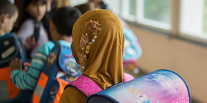 Schülerin mit aufgezogenem Kopftuch vor Klassenzimmer