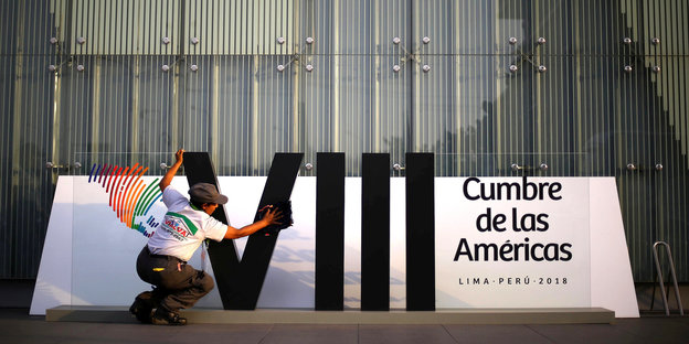 Eine Frau putzt ein Banner im Vorfeld des Amerika-Gipfels in Peru