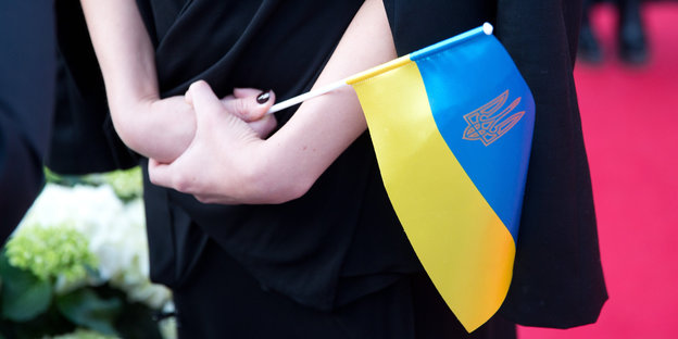 Hände halten die ukrainische Flagge