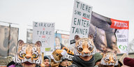 Demonstranten mit Tigermasken tragen Schilder und Transparente.