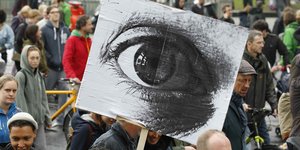 Demonstranten und ein Plakat mit einem Auge