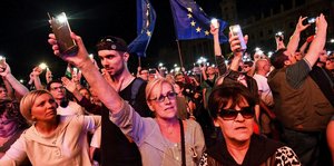 Menschen halten Handys und Europafahnen in die Luft