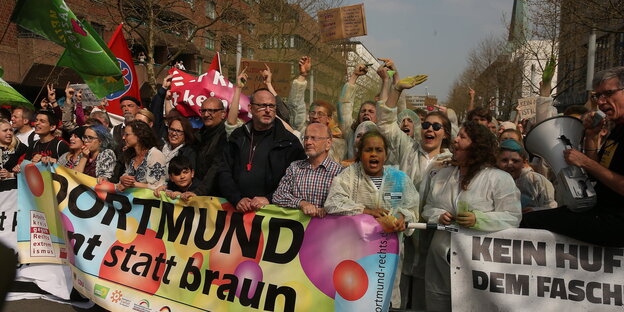 Menschen in Dortmund tragen ein buntes Banner auf dem "Dortmund, bunt statt braun" steht