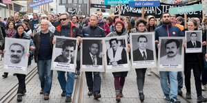 Menschen laufen in einer Reihe und halten Poster mit schwarz-weiß Abbildungen der NSU-Opfer in den Händen