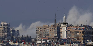 Rauch steigt hinter Damaskus auf, der Himmel aber ist blau