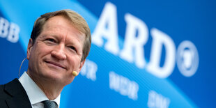 BR-Intendanten Ulrich Wilhelm steht vor einer Wand mit ARD-Logo.