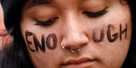 Eine Frau trägt auf ihrem Gesicht den Schriftzug „Enough“ („Genug“)
