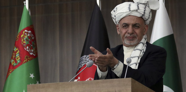 Präsident Ashraf Ghani mit weißem Turban hinter einem Rednerpult